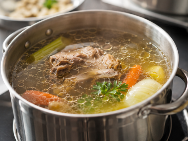 Klare Brühe in einer Schale, zubereitet aus Fleisch, Knochen, Gemüse und Gewürzen als klassische Bouillon.